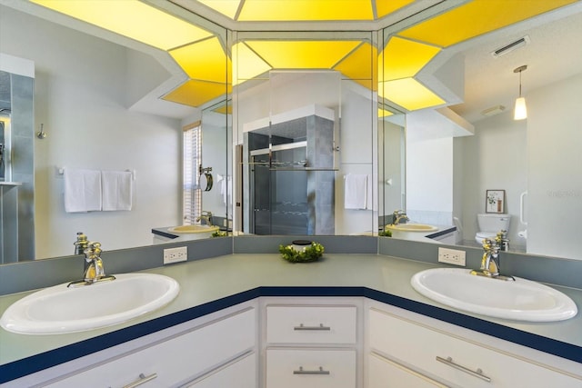 bathroom with double vanity, a sink, visible vents, and a shower stall