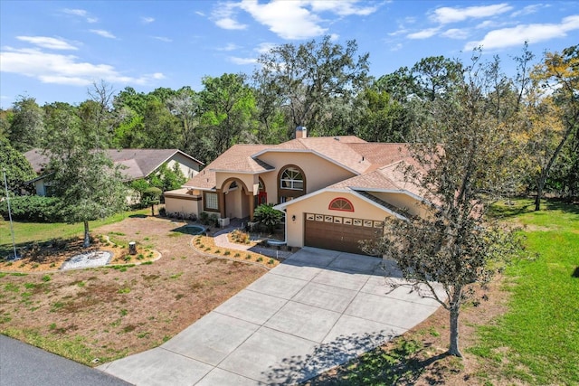 mediterranean / spanish-style home featuring driveway, a garage, a chimney, a front lawn, and stucco siding