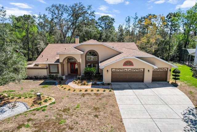 mediterranean / spanish home featuring a garage, a chimney, concrete driveway, and stucco siding