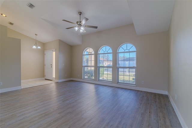 empty room with visible vents, baseboards, lofted ceiling, ceiling fan with notable chandelier, and light wood-style floors