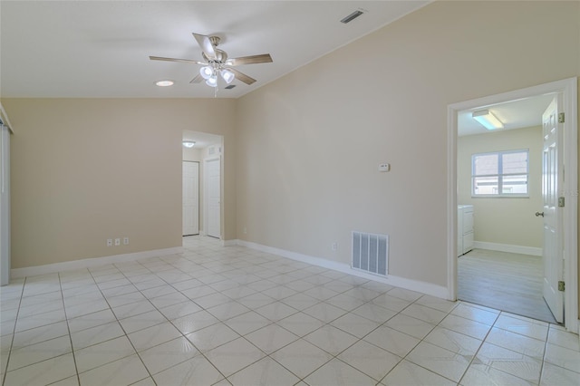 spare room with light tile patterned floors, visible vents, lofted ceiling, and ceiling fan