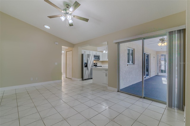 empty room featuring vaulted ceiling, light tile patterned floors, baseboards, and ceiling fan