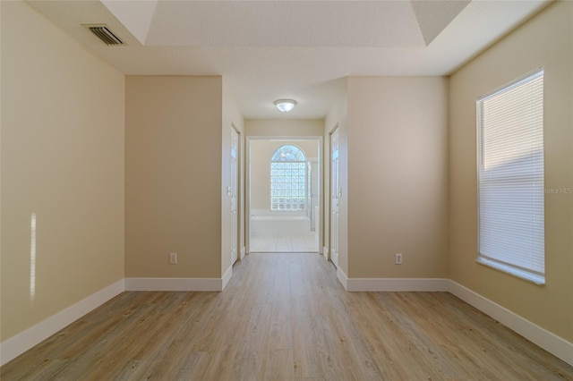 unfurnished room featuring light wood finished floors, visible vents, and baseboards