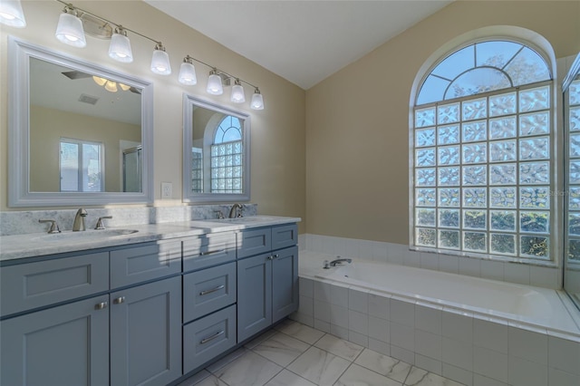 full bath with visible vents, double vanity, a sink, a garden tub, and marble finish floor