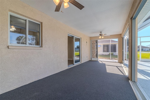 unfurnished sunroom with ceiling fan