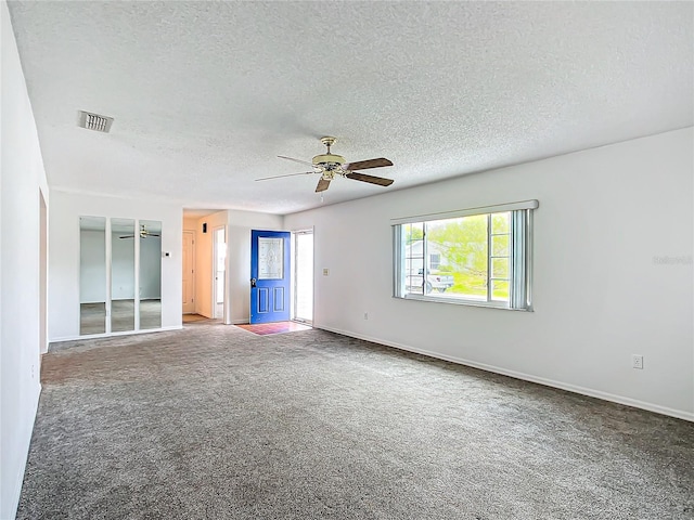 unfurnished room with a textured ceiling, carpet floors, visible vents, baseboards, and a ceiling fan