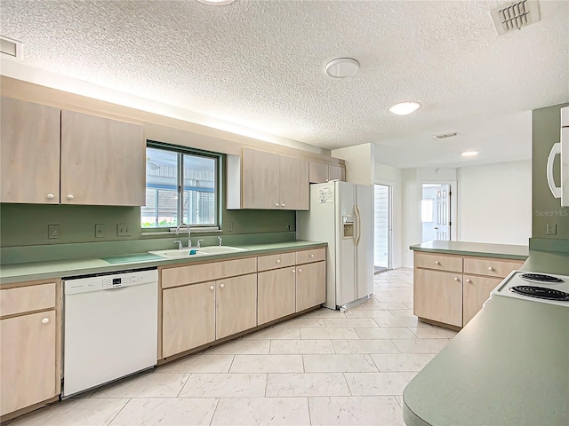 kitchen featuring light brown cabinetry, white appliances, a sink, and visible vents