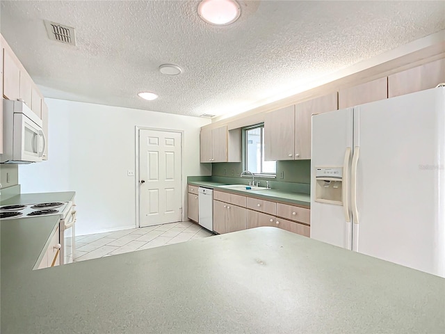 kitchen with white appliances, light tile patterned floors, visible vents, a textured ceiling, and a sink