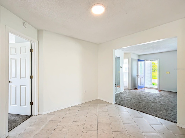 spare room with a textured ceiling and light carpet