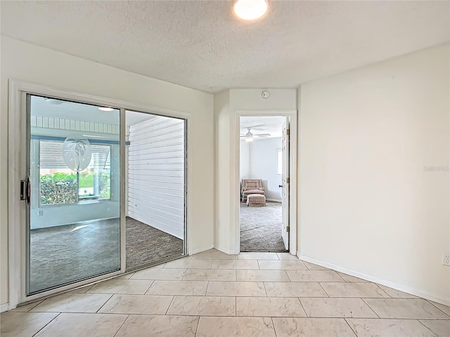 unfurnished room featuring light carpet, a textured ceiling, and baseboards