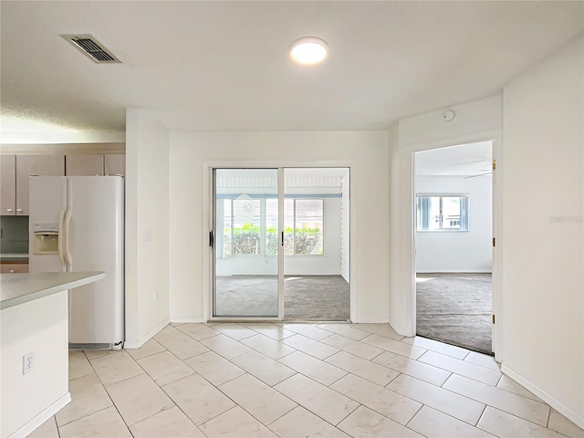 kitchen featuring light countertops, white refrigerator with ice dispenser, and visible vents