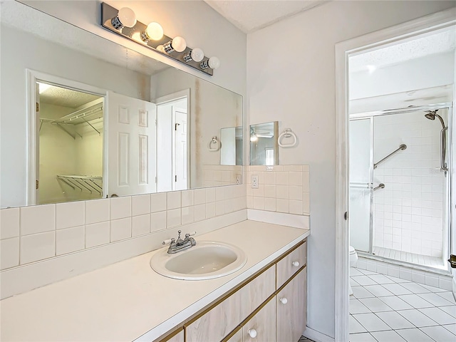 bathroom with toilet, a stall shower, backsplash, and vanity