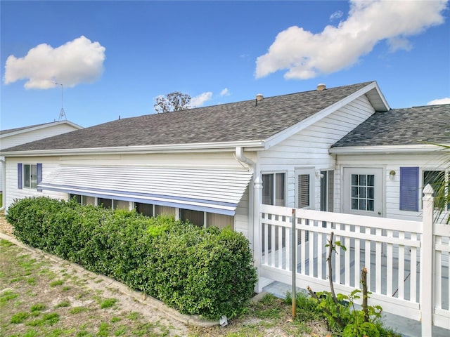 view of side of property with roof with shingles