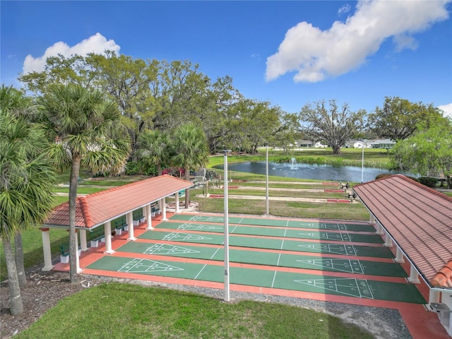 view of community with shuffleboard, a yard, and a water view