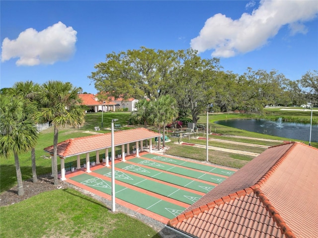 view of community featuring a water view, a yard, and shuffleboard