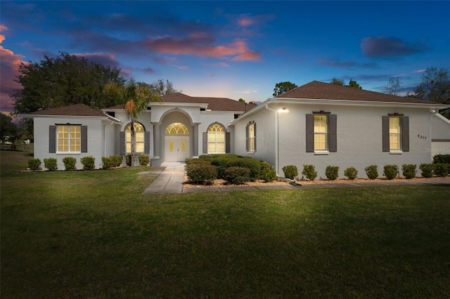 mediterranean / spanish-style house featuring french doors, a front lawn, and stucco siding