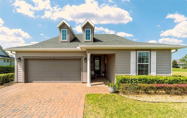 view of front of home featuring a garage, decorative driveway, and a shingled roof