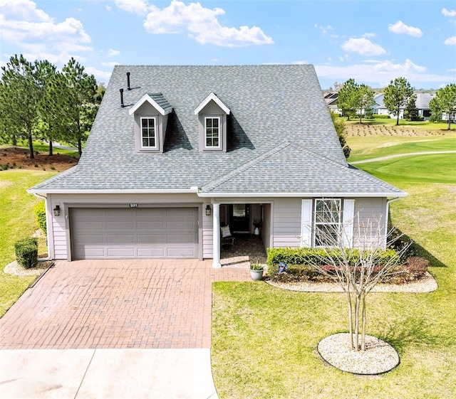 view of front facade featuring decorative driveway, roof with shingles, and a front yard