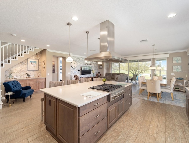 kitchen featuring ornamental molding, open floor plan, island range hood, and stainless steel gas cooktop