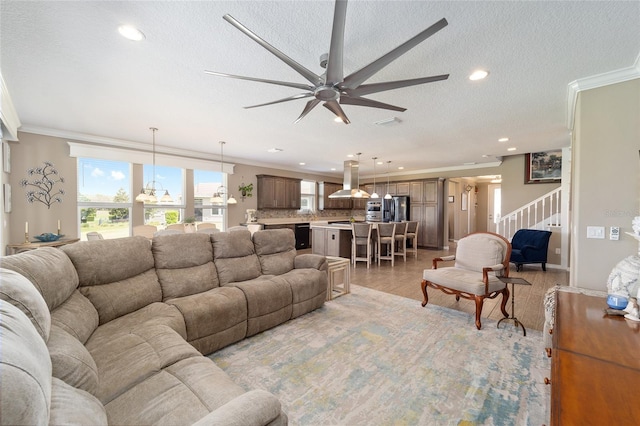 living room with stairs, crown molding, and ceiling fan