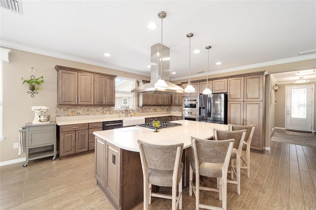 kitchen featuring visible vents, light wood-style flooring, island exhaust hood, backsplash, and appliances with stainless steel finishes