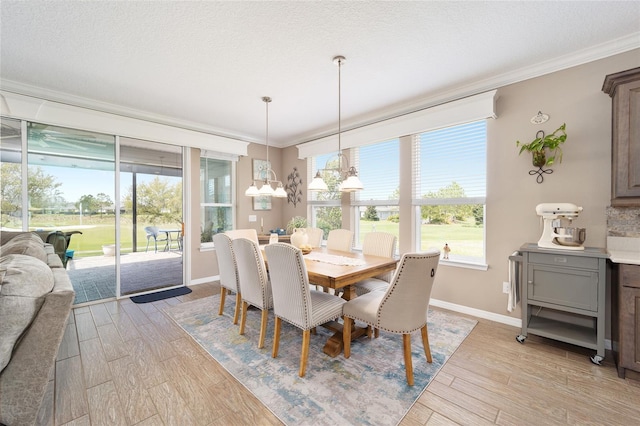 dining room with a chandelier, light wood-style flooring, a textured ceiling, and ornamental molding