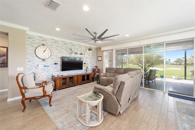 living area with plenty of natural light, an accent wall, ceiling fan, and crown molding