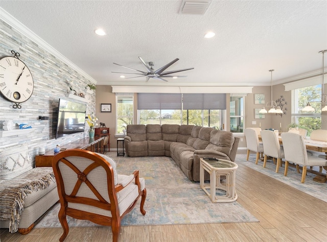 living room featuring wood finished floors, a ceiling fan, visible vents, a textured ceiling, and crown molding