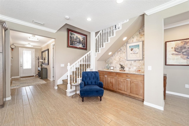 foyer featuring stairway, light wood-style floors, crown molding, and a textured ceiling