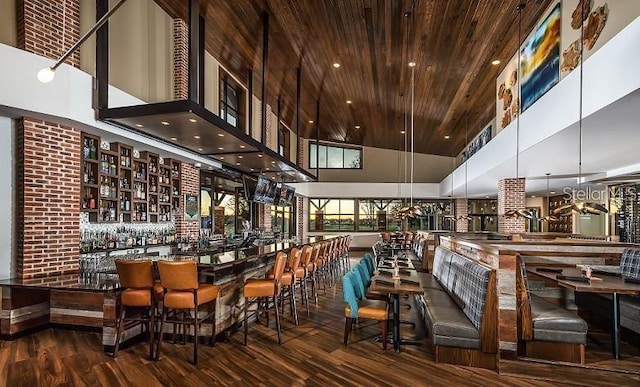 bar with wood finished floors, wood ceiling, a towering ceiling, and a community bar