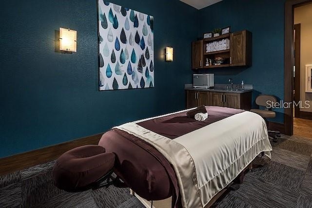 bedroom featuring a sink, indoor wet bar, and wood finished floors