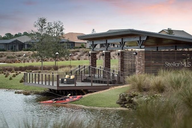 view of dock featuring a deck with water view and a lawn