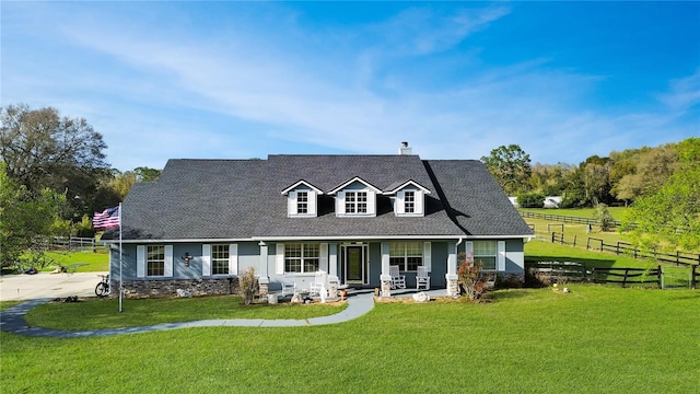 cape cod house with a chimney, roof with shingles, fence, a front lawn, and a porch