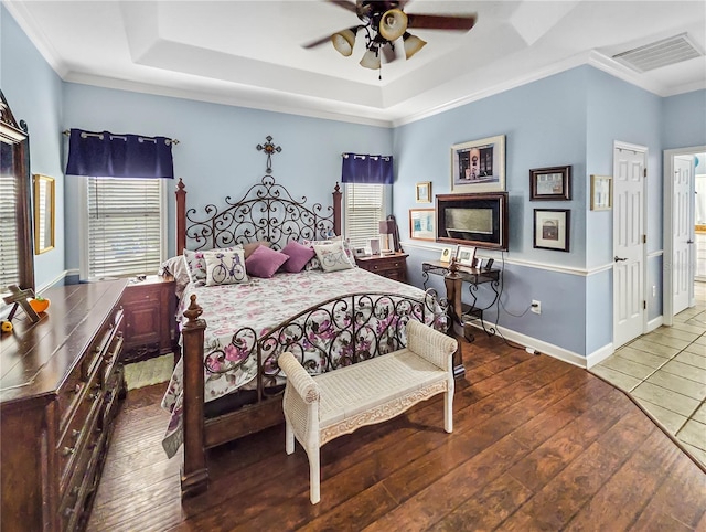 bedroom featuring a tray ceiling, visible vents, hardwood / wood-style floors, and ornamental molding