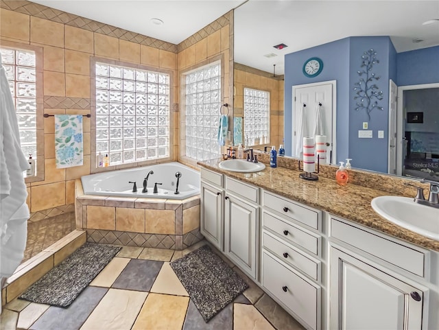 full bathroom with tile patterned flooring, double vanity, a sink, and a bath