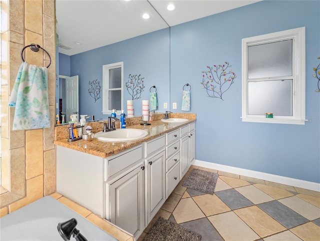 bathroom with double vanity, a sink, and baseboards