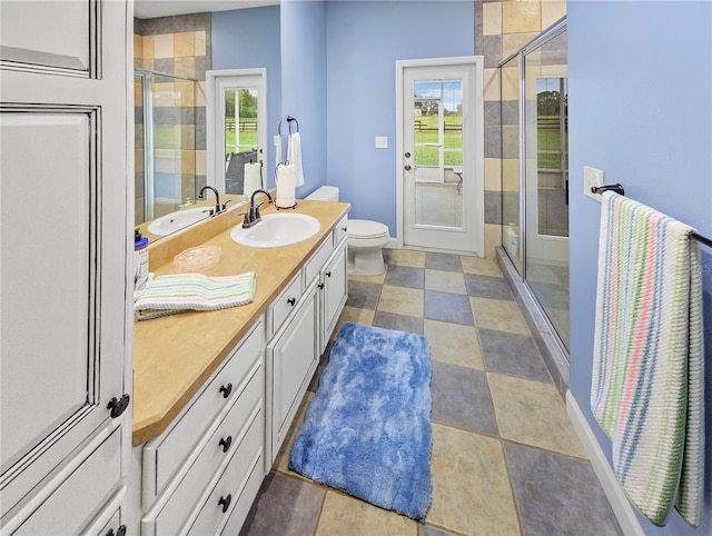 bathroom featuring toilet, a shower stall, vanity, and a healthy amount of sunlight