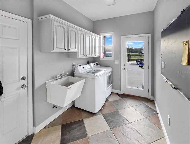 washroom with baseboards, cabinet space, independent washer and dryer, and a sink