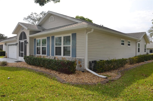 view of home's exterior with a garage, stone siding, a yard, and driveway