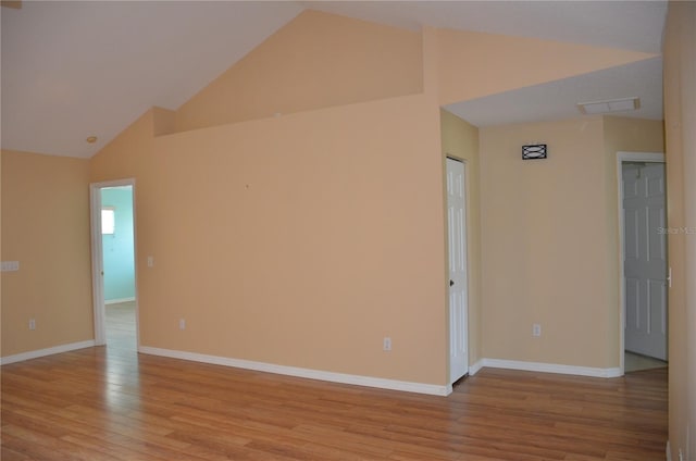 spare room featuring light wood-style floors, visible vents, high vaulted ceiling, and baseboards