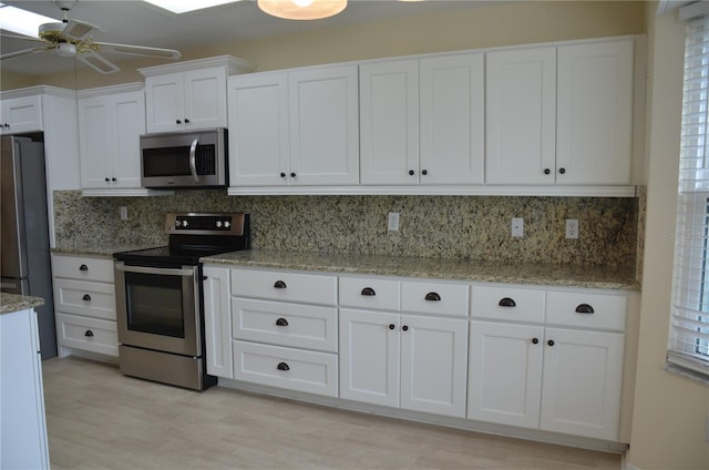 kitchen featuring stainless steel appliances, decorative backsplash, and white cabinets