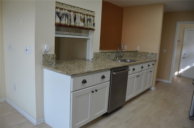 kitchen with white cabinets, dishwasher, light wood-style flooring, light stone countertops, and a sink