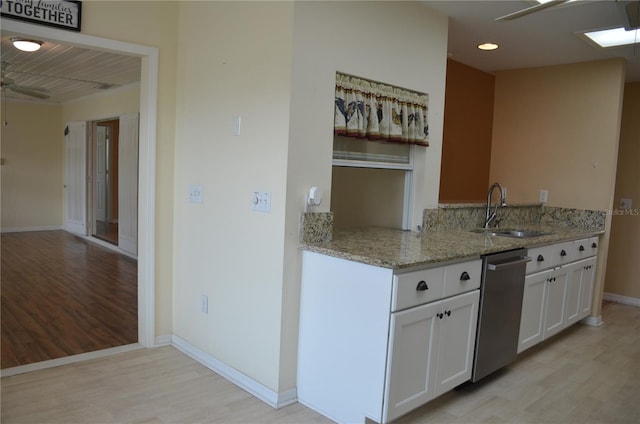 kitchen featuring light stone counters, a ceiling fan, white cabinetry, a sink, and dishwasher