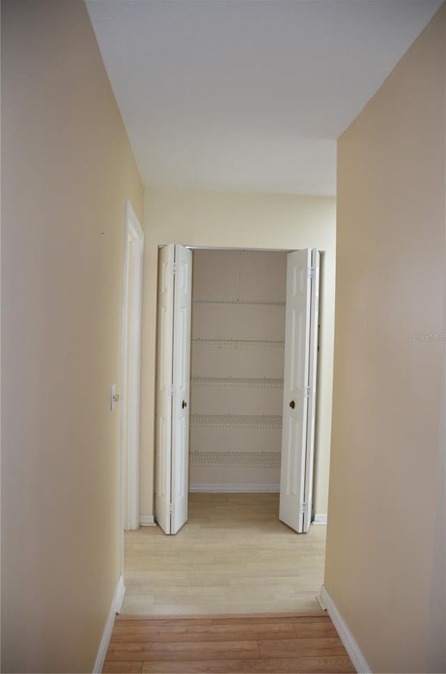 corridor with wood finished floors and baseboards