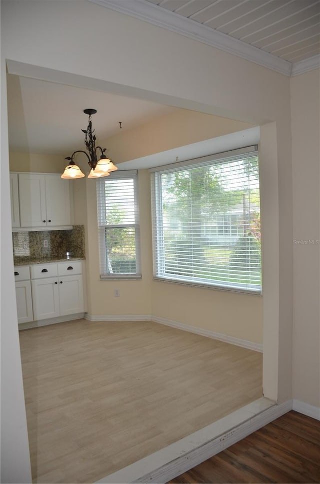 kitchen with a notable chandelier, light wood-style flooring, decorative backsplash, ornamental molding, and white cabinets