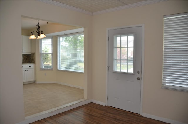 entryway featuring ornamental molding, baseboards, an inviting chandelier, and wood finished floors