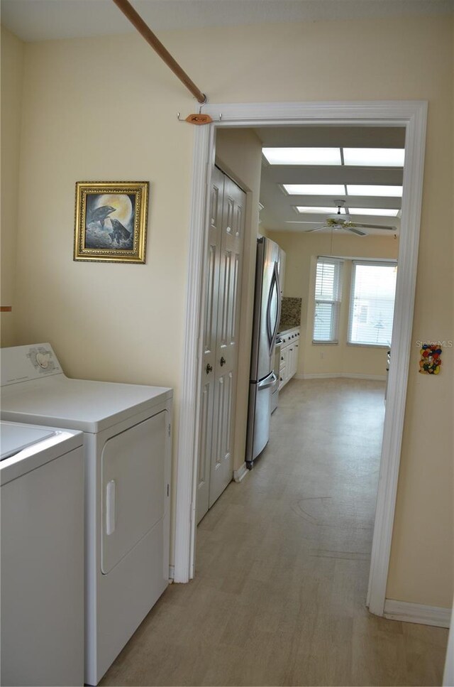 clothes washing area with laundry area, baseboards, a ceiling fan, light wood-type flooring, and separate washer and dryer