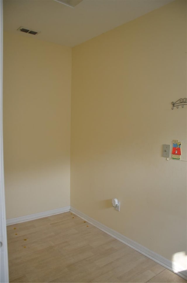 empty room featuring light wood-style flooring, visible vents, and baseboards