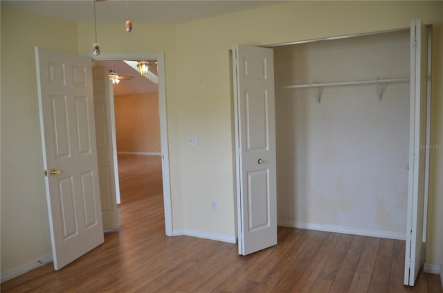 unfurnished bedroom with a closet, baseboards, and wood finished floors