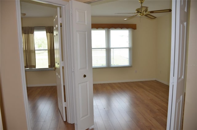 unfurnished room featuring ceiling fan, baseboards, and wood finished floors